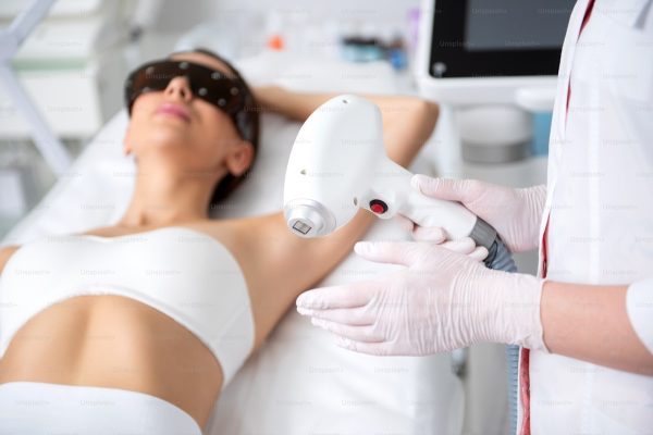 Laser hair removal device treating underarm area in clinic